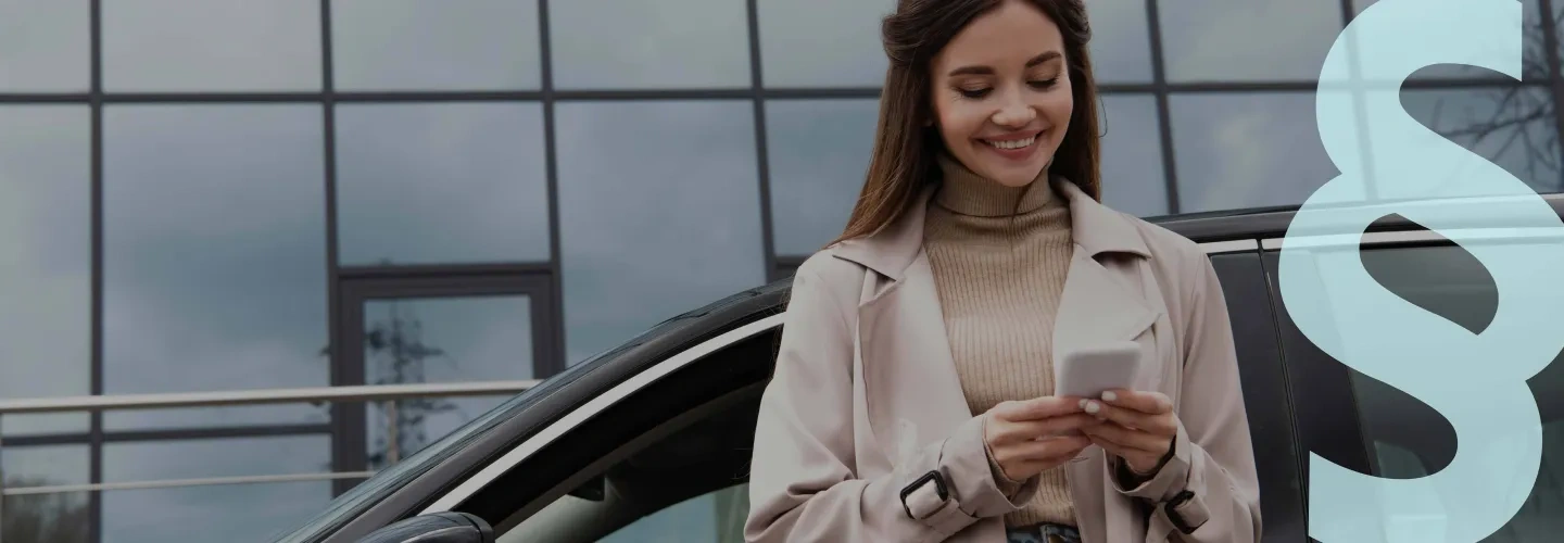 Nainen katsoo kännykkää lasiseinäisen rakennuksen edessä